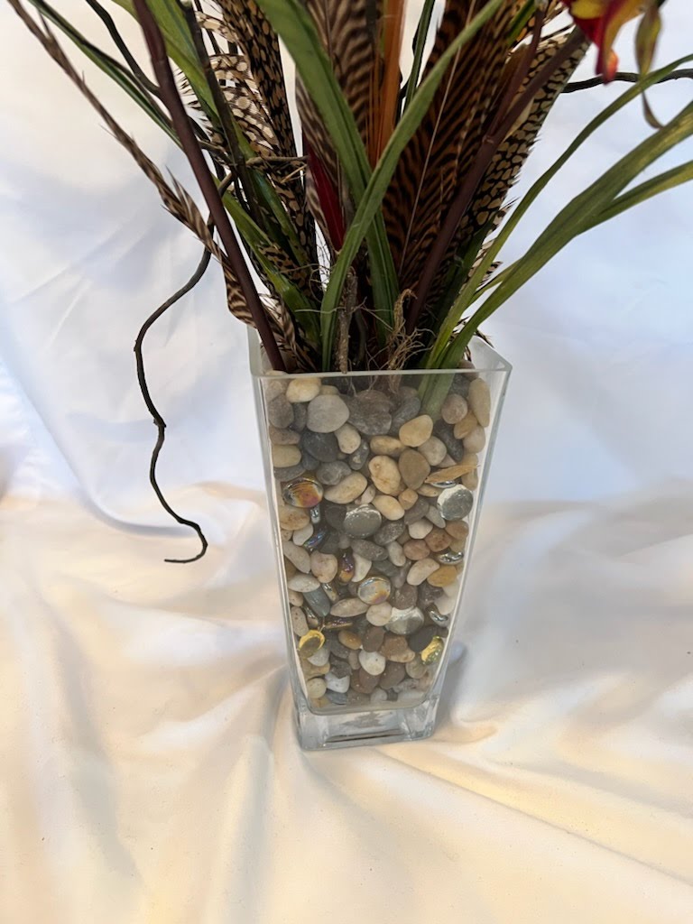 Clear vase with pebbles and feathers